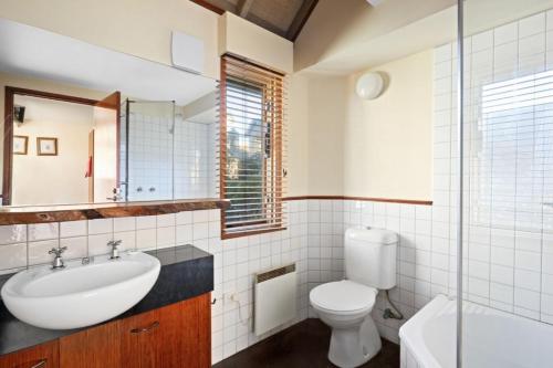 a bathroom with a sink and a toilet and a mirror at Cobungra Chalet in Mount Hotham