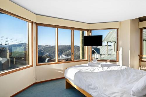 a bedroom with a bed and a large window at Cobungra Chalet in Mount Hotham