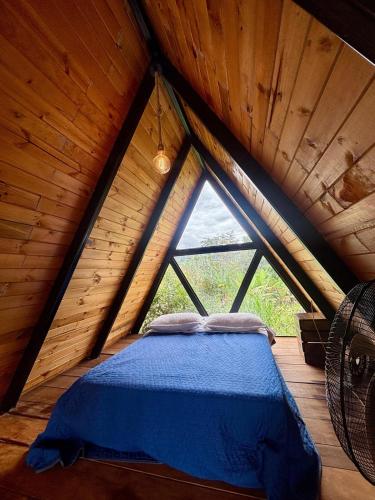 a bed in a wooden room with a large window at Glamping Encanto Amazónico Macas in General Proaño