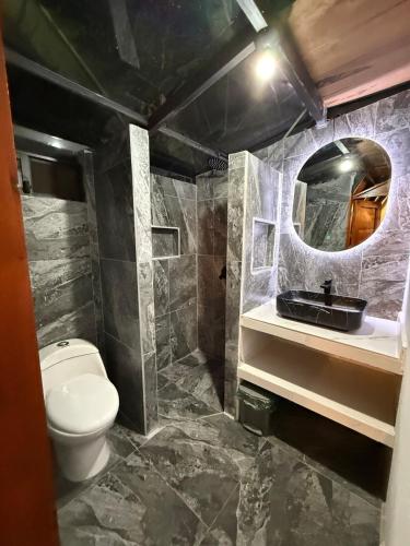 a bathroom with a toilet and a sink and a mirror at Glamping Encanto Amazónico Macas in General Proaño
