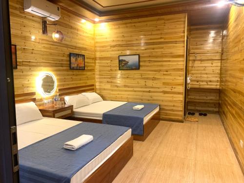 two beds in a room with wooden walls at Huy Hùng Cô Tô in Nam Cap