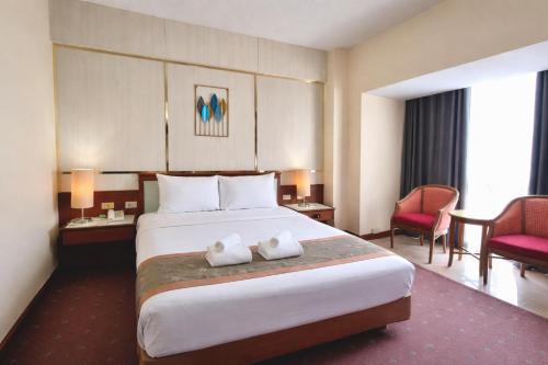ein Hotelzimmer mit einem großen Bett und zwei Handtüchern in der Unterkunft Asian Hotel in Hat Yai