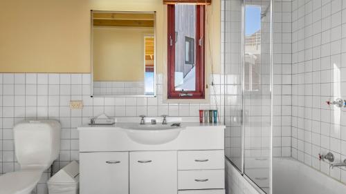a bathroom with a sink and a tub and a toilet at Gundanora Chalet in Mount Hotham
