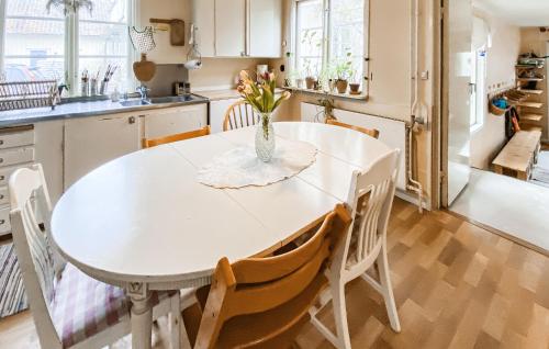 a kitchen with a white table with a vase of flowers on it at 2 Bedroom Nice Home In Glömminge in Glömminge