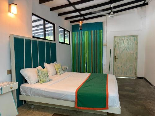 a bedroom with a bed with a green curtain and a door at Angelica Villa in Bentota