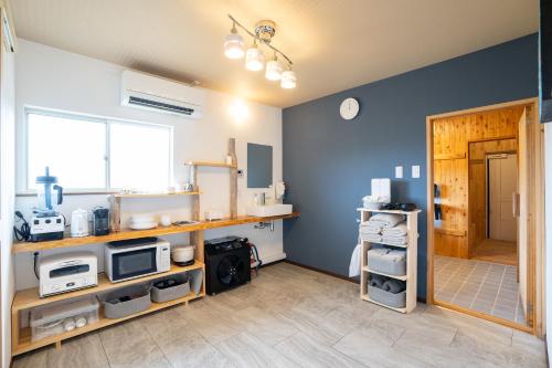 a room with a kitchen with blue walls at HOSHIとUmitoはサウナで整う完全プライベート1棟貸でプロジェクター完備 in Nakijin
