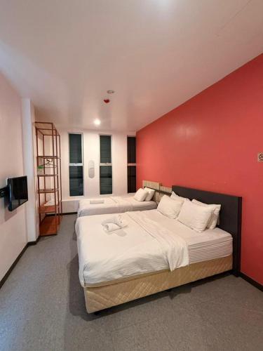 two beds in a room with a red wall at TT Dorf Hotel Taiping in Taiping