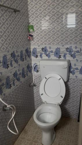 a bathroom with a toilet with blue flowers on the wall at Jacobs Cottage KG-F1 in Thiruchendur