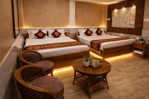 a hotel room with two beds and a table and chairs at Tripathi's Rampath Inn Ayodhya in Ayodhya