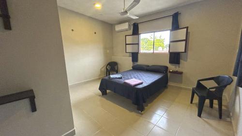 ein Schlafzimmer mit einem Bett, zwei Stühlen und einem Fenster in der Unterkunft Luz Sofia Bacalar in Bacalar
