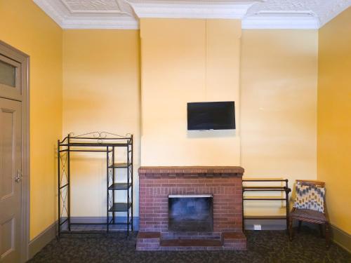 a room with a fireplace and a tv on a wall at Cessnock Hotel Hunter Valley in Cessnock