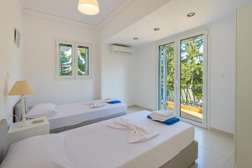 two beds in a white room with a window at Villa Giovanni in Faliraki