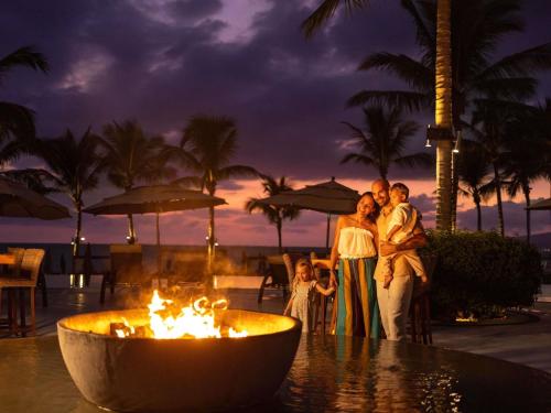 a family standing in front of a fire fountain at a resort at Marival Distinct All-Suites & World Spa - Handwritten Collection in Nuevo Vallarta