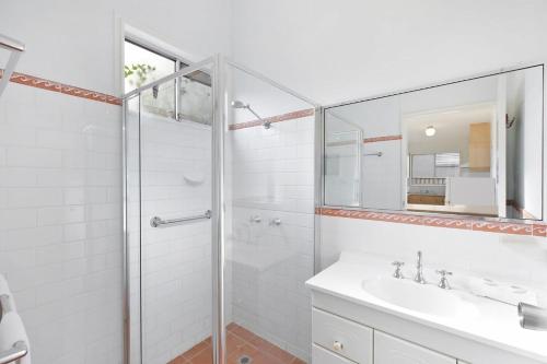 a white bathroom with a shower and a sink at Lakes Edge Cottage Pet Friendly Waterfront Escape in Budgewoi