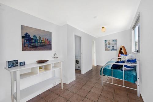 a white room with a bed and a desk at Lakes Edge Cottage Pet Friendly Waterfront Escape in Budgewoi
