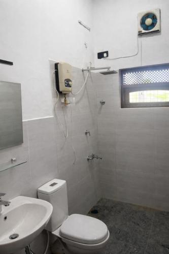 a white bathroom with a toilet and a sink at Long Villa in Kandy