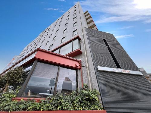 a building with a sign on the side of it at KOKO STAY Sagamihara - formerly Hotel Wing International Sagamihara in Sagamihara