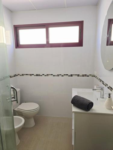 a bathroom with a toilet and a sink and a window at Atico playa de Miramar in Miramar