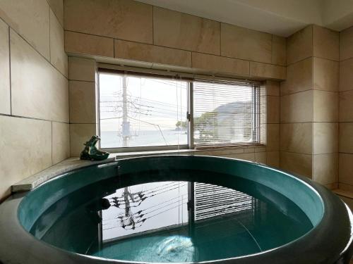 a bath tub in a bathroom with a window at ゲストハウス&café chiuwo in Kawazu