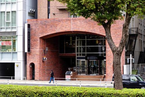 a person walking in front of a brick building at KOKO HOTEL Nagoya Marunouchi - formerly Hotel Wing International Nagoya in Nagoya