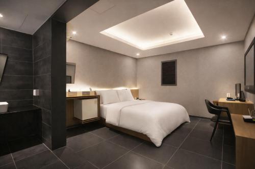 a hotel room with a bed and a desk and a sink at Zenith Hotel Bupyeong in Incheon