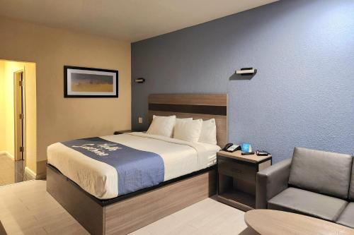 a hotel room with a bed and a chair at Days Inn by Wyndham Freeport in Freeport