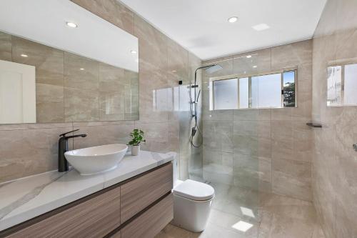 a bathroom with a sink and a toilet and a shower at Toukley Waterfront House in Toukley