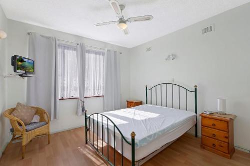 a bedroom with a bed and a chair and a ceiling fan at The Sands Apartment 6 in The Entrance
