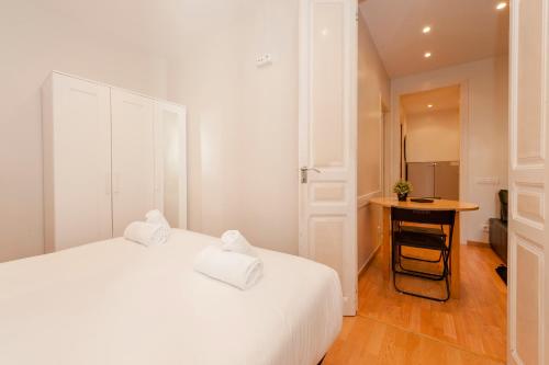 a white bedroom with a white bed and a table at Bbarcelona Apartments Plaza España Flats in Barcelona