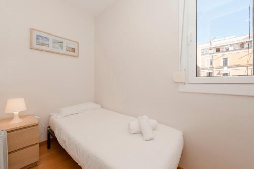 a white bedroom with a bed and a window at Bbarcelona Apartments Plaza España Flats in Barcelona