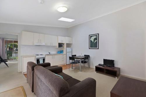 a living room with a couch and a table and a kitchen at Surfside Palms 14 in The Entrance
