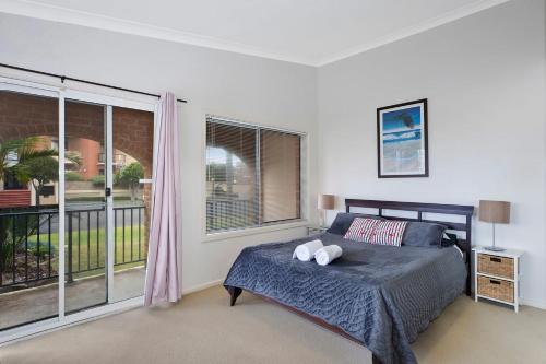 a bedroom with a bed and a large window at Surfside Palms 14 in The Entrance
