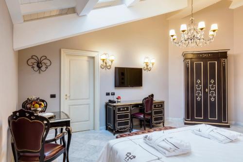 a bedroom with a bed and a desk and a tv at Grand Hotel di Parma | UNA Esperienze in Parma