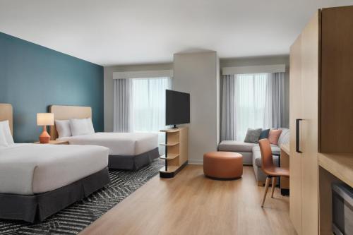 a hotel room with two beds and a couch at Hyatt House Schenectady / Mohawk Harbor in Schenectady