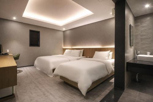 two beds in a hotel room with a sink at Zenith Hotel Bupyeong in Incheon