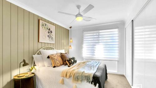 a bedroom with a bed and a ceiling fan at Natuna Lakeside Retreat in Budgewoi