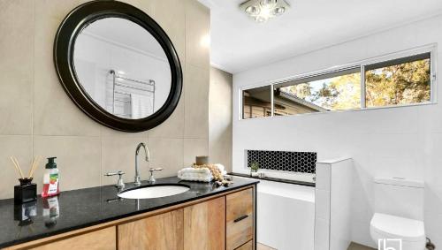 a bathroom with a sink and a mirror at Natuna Lakeside Retreat in Budgewoi