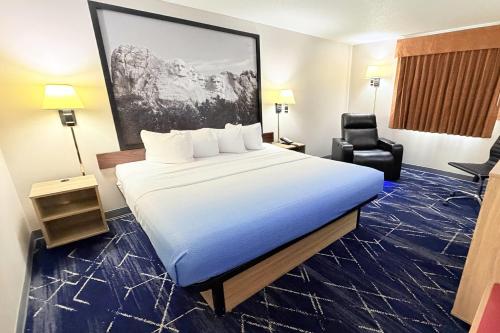 a hotel room with a large bed and a chair at Super 8 by Wyndham Hot Springs in Hot Springs