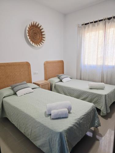 a bedroom with two beds and a clock on the wall at Apartamento playa de Miramar in Miramar