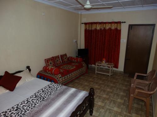 een slaapkamer met een bed, een stoel en een bank bij Green Villa in Virajpet