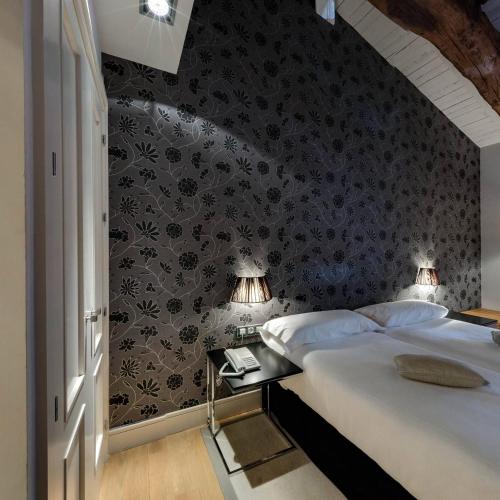 a bedroom with a bed and a wall with floral wallpaper at Hotel Palacio Muñatones in Muskiz