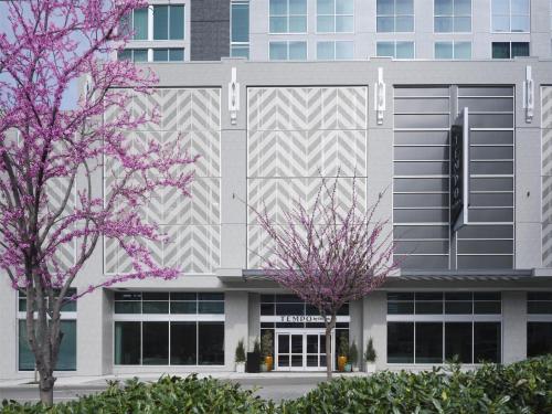 a building with purple flowering trees in front of it at Tempo By Hilton Nashville Midtown in Nashville