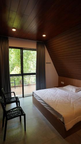 a bedroom with a bed and a chair and a window at Lostcabins in Vallikavungal
