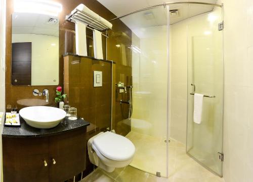 a bathroom with a toilet and a sink and a shower at Delta Suites in Durgāpur