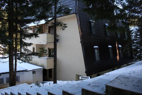 a building with snow on the ground in front of it at Apartmani Čolić Vlašić in Vlasic