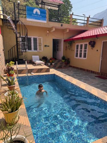 a man in a swimming pool next to a house at Shivay Hotel & Resort in Dhārchula