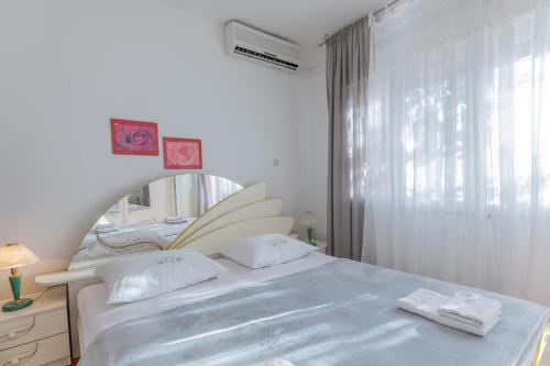 a white bedroom with a bed and a mirror at Tinka, Zimmer No 2 in Starigrad