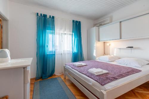 a bedroom with a large bed with blue curtains at Tinka, Zimmer No 6 in Starigrad