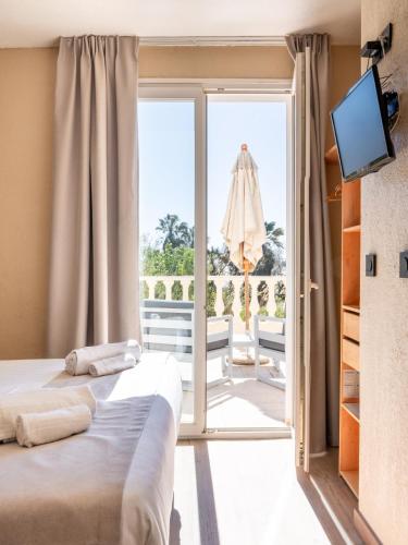 a bedroom with a bed and a sliding glass door at Hôtel de la Mer in Hyères