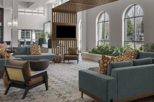 a lobby with couches and chairs and a flat screen tv at Embassy Suites by Hilton Tuscaloosa Alabama Downtown in Tuscaloosa